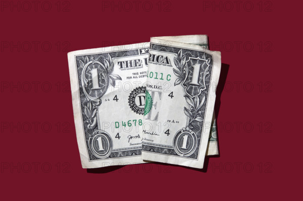 Studio shot of folded one dollar bill on red background