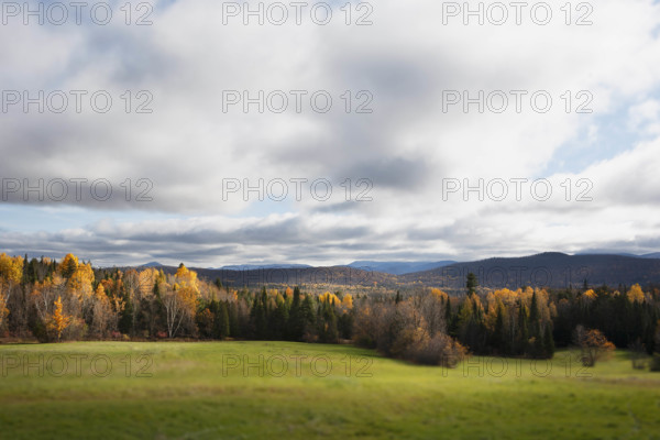 USA, New York, Saranac Lake, Clouds over fields and trees in Autumn