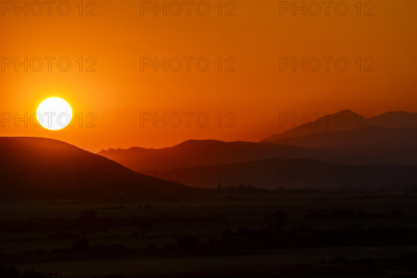 USA, Idaho, Bellevue, Setting sun over hills against orange sky