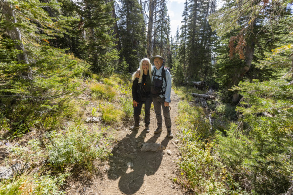 USA, Idaho, Sun Valley, Portrait of smiling senior couple standing on footpath in forest