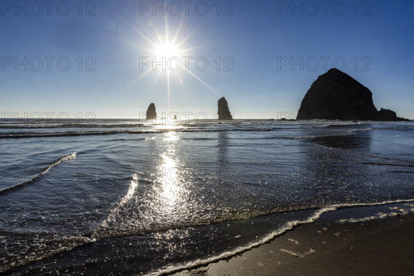 USA, Oregon, Sun setting over ocean and empty Cannon Beach