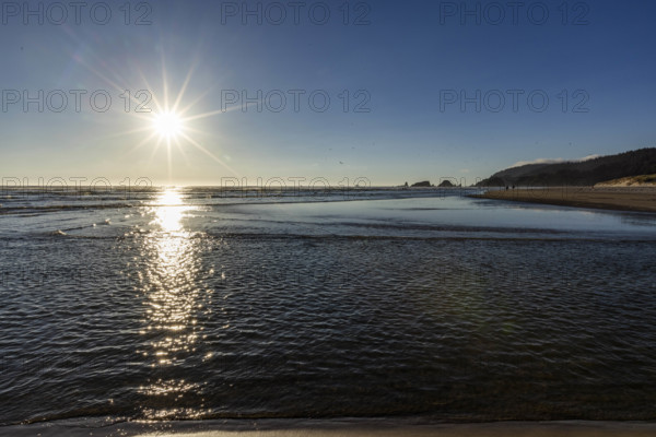 USA, Oregon, Sun setting over ocean and empty Cannon Beach