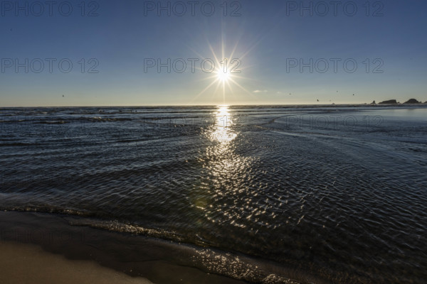 USA, Oregon, Sun setting over ocean and empty Cannon Beach