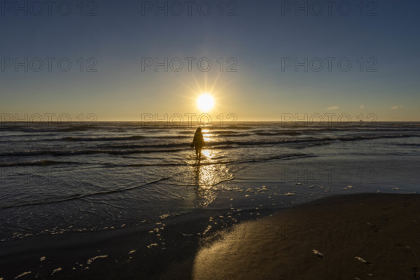 USA, Oregon, Cannon Beach, Woman wading in surf at sunset