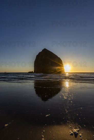 USA, Oregon, Sun setting behind haystack rock on Cannon Beach