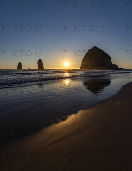 USA, Oregon, Sun setting behind haystack rock on Cannon Beach