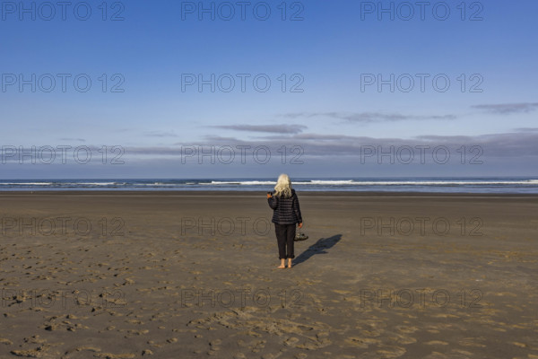 USA, Oregon, Newport, Rear view of woman standing on empty beach