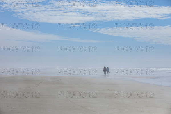 USA, Oregon, Newport, Rear view of couple walking on empty beach