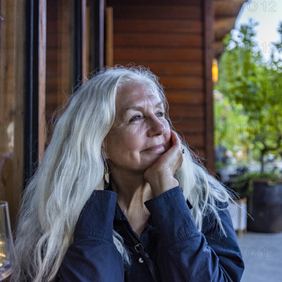 Portrait of smiling senior woman with long white hair sitting outdoors