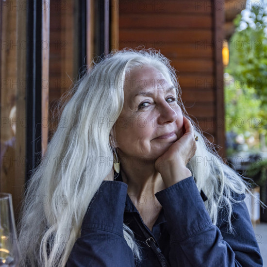 Portrait of smiling senior woman with long white hair sitting outdoors