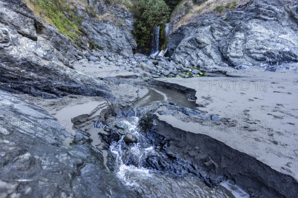 USA, Oregon, Brookings, Creek running across sand to Pacific Ocean on Oregon Coast