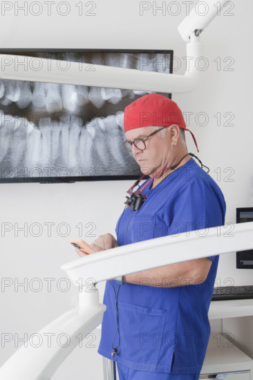 Dentist looking at smartphone after analyzing X-ray