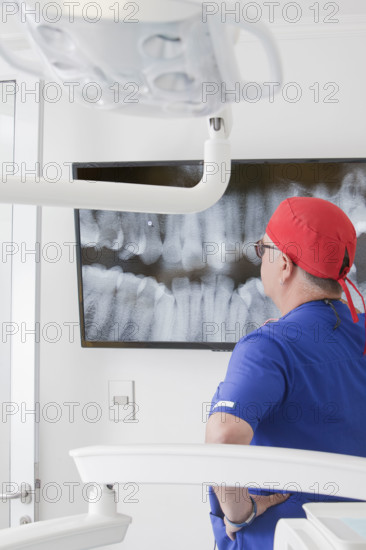 Dentist analyzing dental X-ray on screen