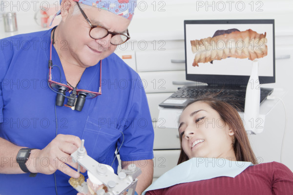 Dentist explaining dental hygiene to patient using jaw model