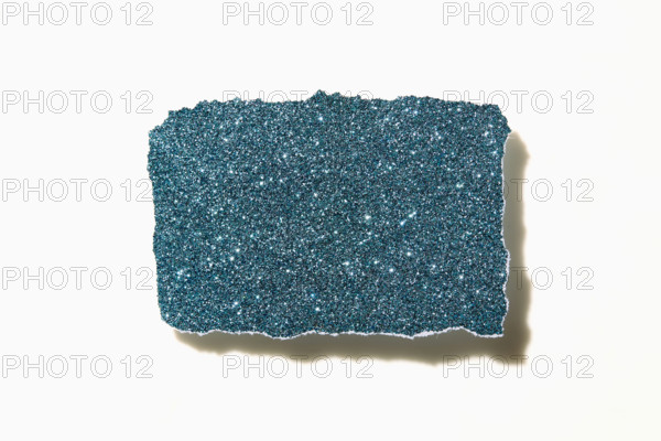 Torn blue glitter paper on white background