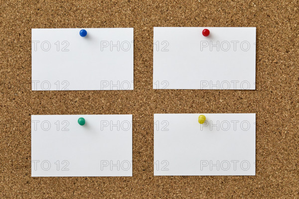 Blank pieces of paper attached to cork board with colorful push pins