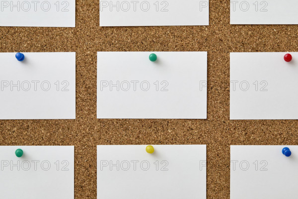 Blank pieces of paper attached to cork board with colorful push pins