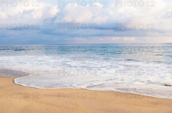 Mexico, Oaxaca State, Puerto Escondido, Costa Chica, Cumulus clouds over ocean waves on empty beach