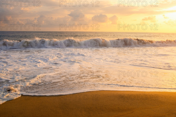 Mexico, Oaxaca State, Puerto Escondido, Costa Chica, Clouds over ocean waves on empty beach at sunset