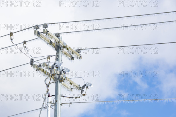Utility pole with icicles against sky