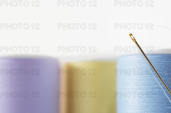 Studio shot of needle and colorful spools of threads