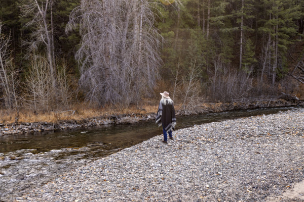 USA, Idaho, Sun Valley, Rear view of woman in wool poncho on riverbank