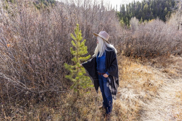 USA, Idaho, Sun Valley, Woman in wool poncho on footpath in landscape