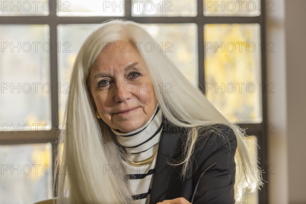 USA, Idaho, Boise, Portrait of smiling senior woman with long white hair in office