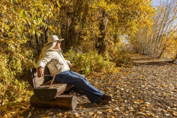 USA, Idaho, Bellevue, Senior woman relaxing on bench in landscape in autumn