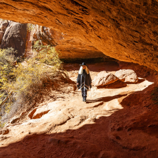 USA, Utah, Zion National Park, Smiling woman in poncho and hat hiking in Zion Overlook Trail