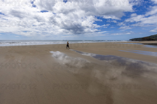 Costa Rica, Guanacaste, Playa Grande, Woman walking on empty beach at low tide