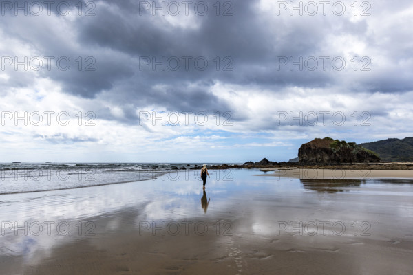 Costa Rica, Guanacaste, Playa Grande, Woman walking on empty beach at low tide