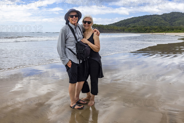 Costa Rica, Guanacaste, Playa Grande, Portrait of smiling senior couple on empty beach at low tide