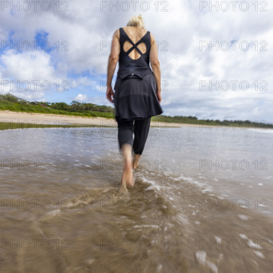 Costa Rica, Guanacaste, Playa Grande, Rear view of woman walking on empty beach