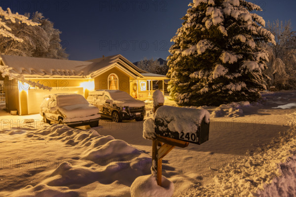 USA, Idaho, Bellevue, Illuminated suburban house and cars covered with snow at night