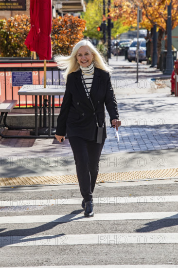 USA, Idaho, Boise, Smiling senior blond businesswoman crossing downtown street