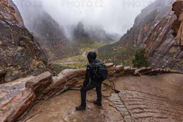 USA, Utah, Zion National Park, Rear view of female hiker in snowstorm on trail to Angels Landing