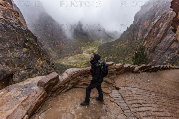 USA, Utah, Zion National Park, Female hiker catching snowflakes on tongue on trail to Angels Landing