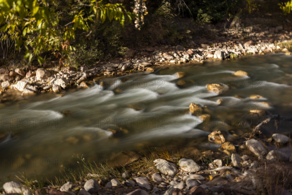 USA, Utah, Zion National Park, Rocks in shallow Virgin River on sunny afternoon, motion blur