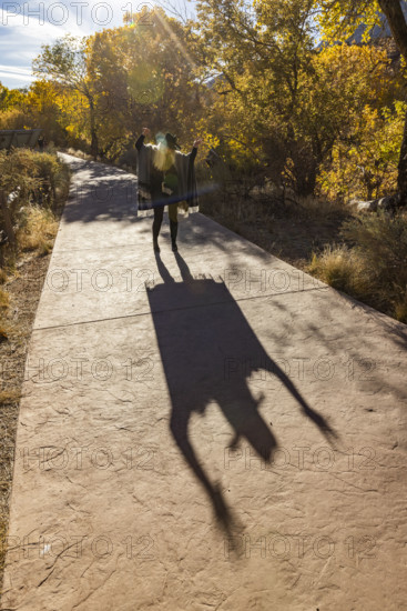 USA, Utah, Zion National Park, Senior woman in poncho making shadows on park walkway