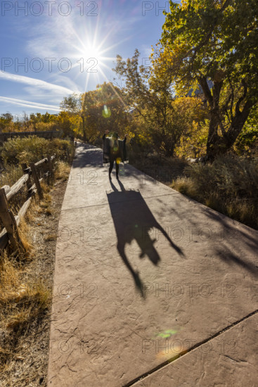 USA, Utah, Zion National Park, Senior woman in poncho making shadows on park walkway