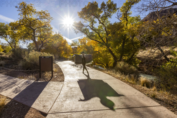 USA, Utah, Zion National Park, Senior woman in poncho making shadows on park walkway