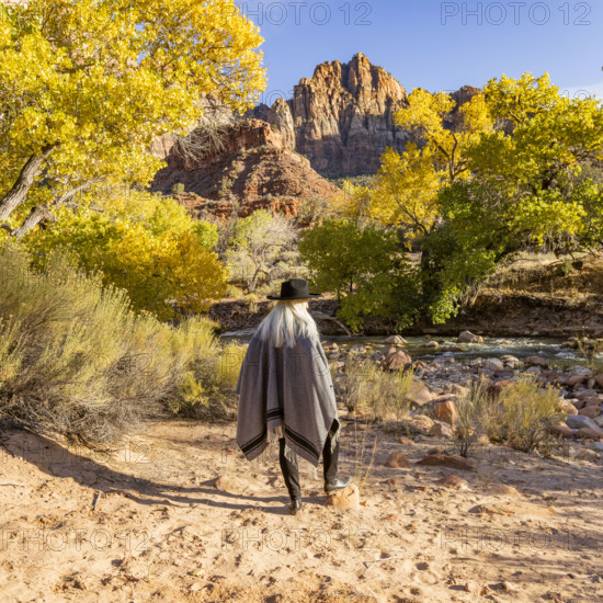 USA, Utah, Zion National Park, Rear view of woman in poncho and hat standing near Virgin River