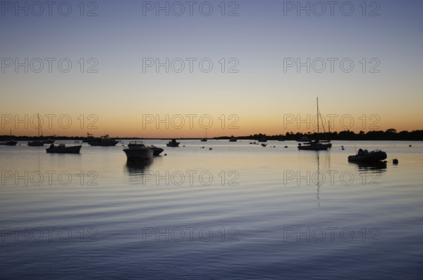 USA, Massachusetts, Nantucket, Boats on calm Polpis Harbor at sunset