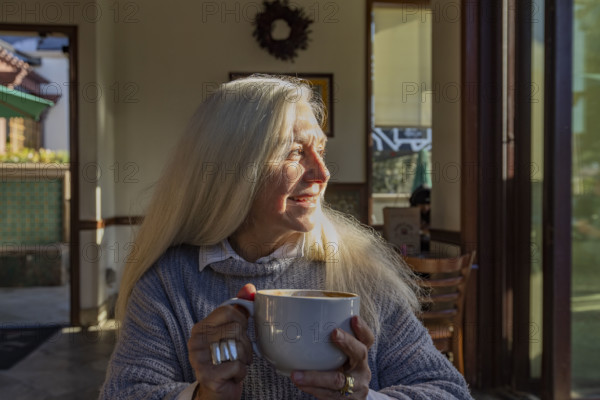 Portrait of smiling senior woman holding mug of coffee at home
