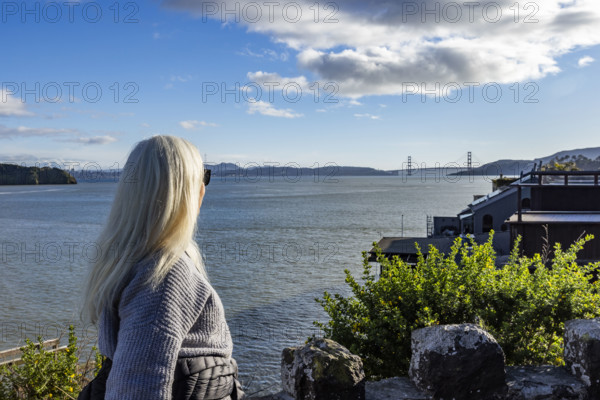 USA, California, Tiburon, Senior woman viewing Golden Gate Bridge in distance across San Francisco Bay