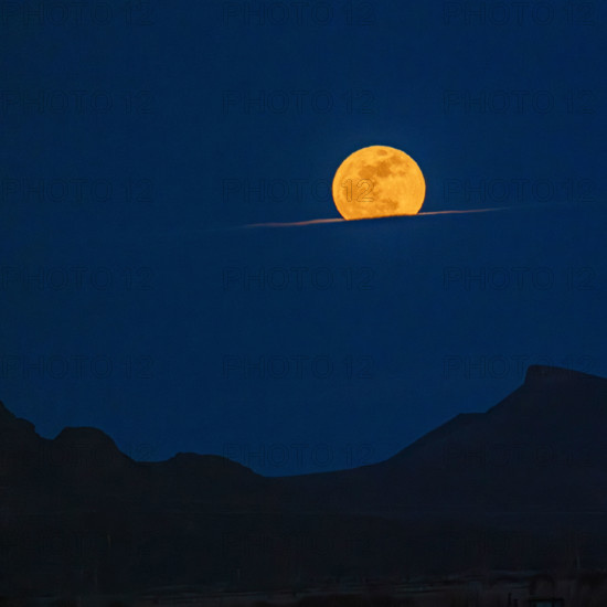 Pink Moon rising over cloud bank. Bellevue, Idaho, USA.