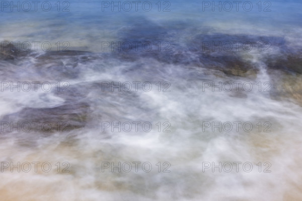 Close-up of motion blurred ocean water on sand. Kona, Hawaii, USA.