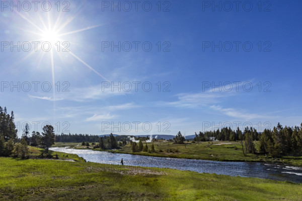 Sun on blue sky over Firehole River . , Wyoming, USA.