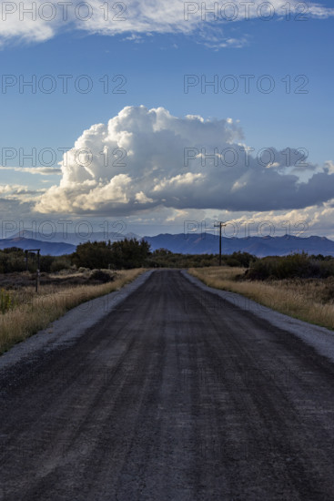 White puffy clouds over empty rural road and mountains. Bellevue, Idaho, USA.
